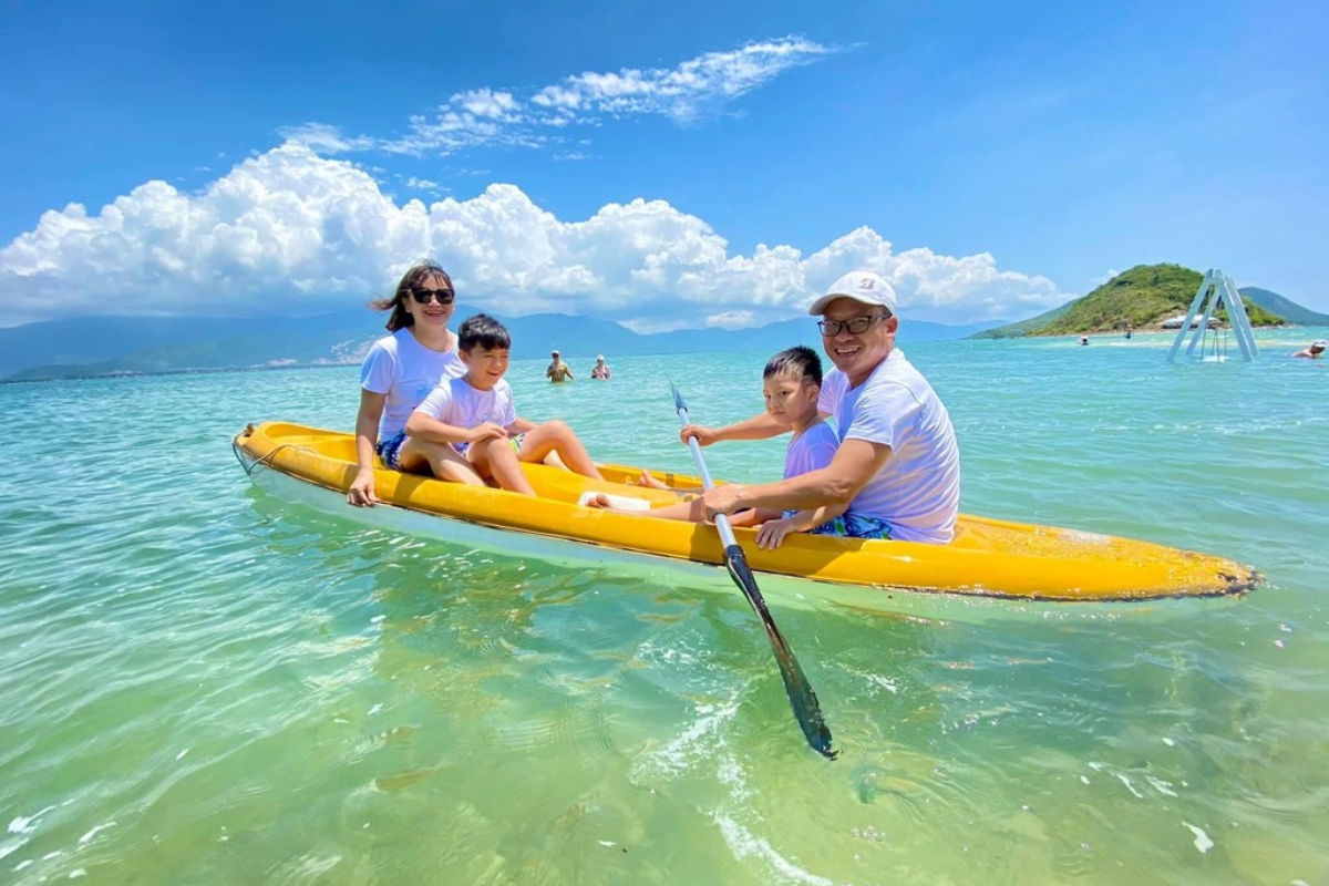Tourists kayaking near the shore of Diep Son Island with calm waters and blue sky